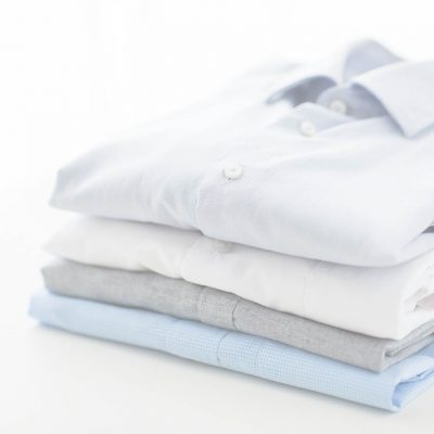 ironing, laundry, clothes, housekeeping and objects concept - close up of ironed and folded shirts on table at home