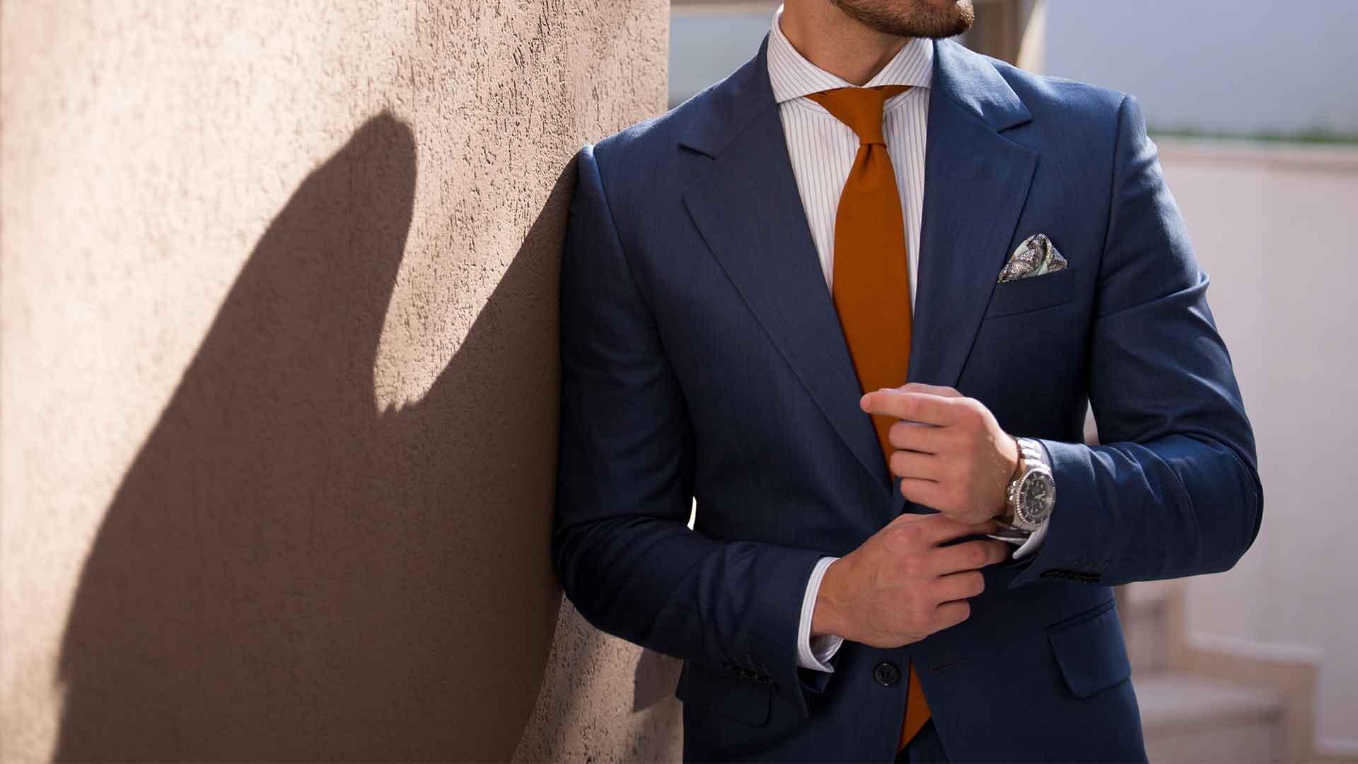Man in a pressed navy suit and orange tie